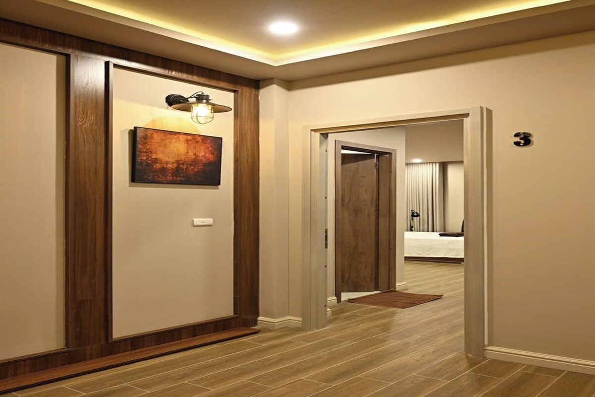 Um corredor com piso de madeira, um quadro na parede e uma porta com o número 3.