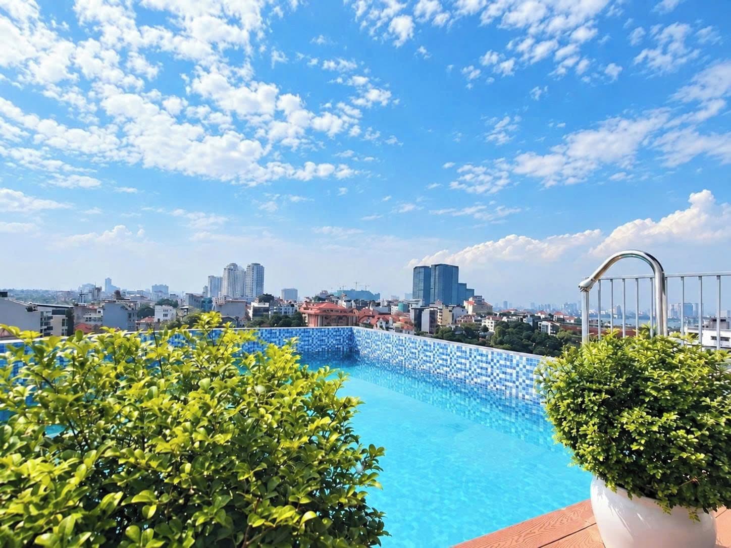 Una piscina en la azotea con vistas a la ciudad, rodeada de vegetación.