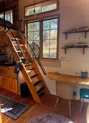 A wooden staircase leading to a kitchen with a window, a wooden dining table, and a chair.