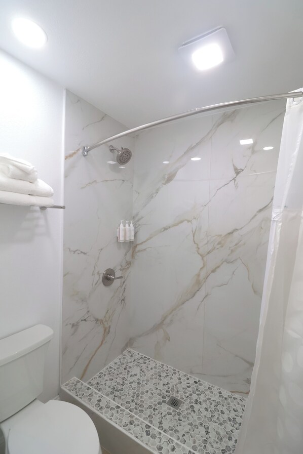 A bathroom with a shower, toilet, and a towel rack. - Mustang Queen Bedroom in the Heart of SLO (San Luis Obispo)