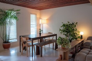 Een eetgedeelte met een houten tafel, stoelen, een bank en potplanten.