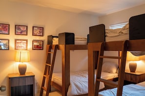 A bunk bed room with a ladder, a bedside table with a lamp, and framed artwork on the wall. - Creekside Austin Retreat. Sauna, Cold Plunge & Wooded Views (Austin)