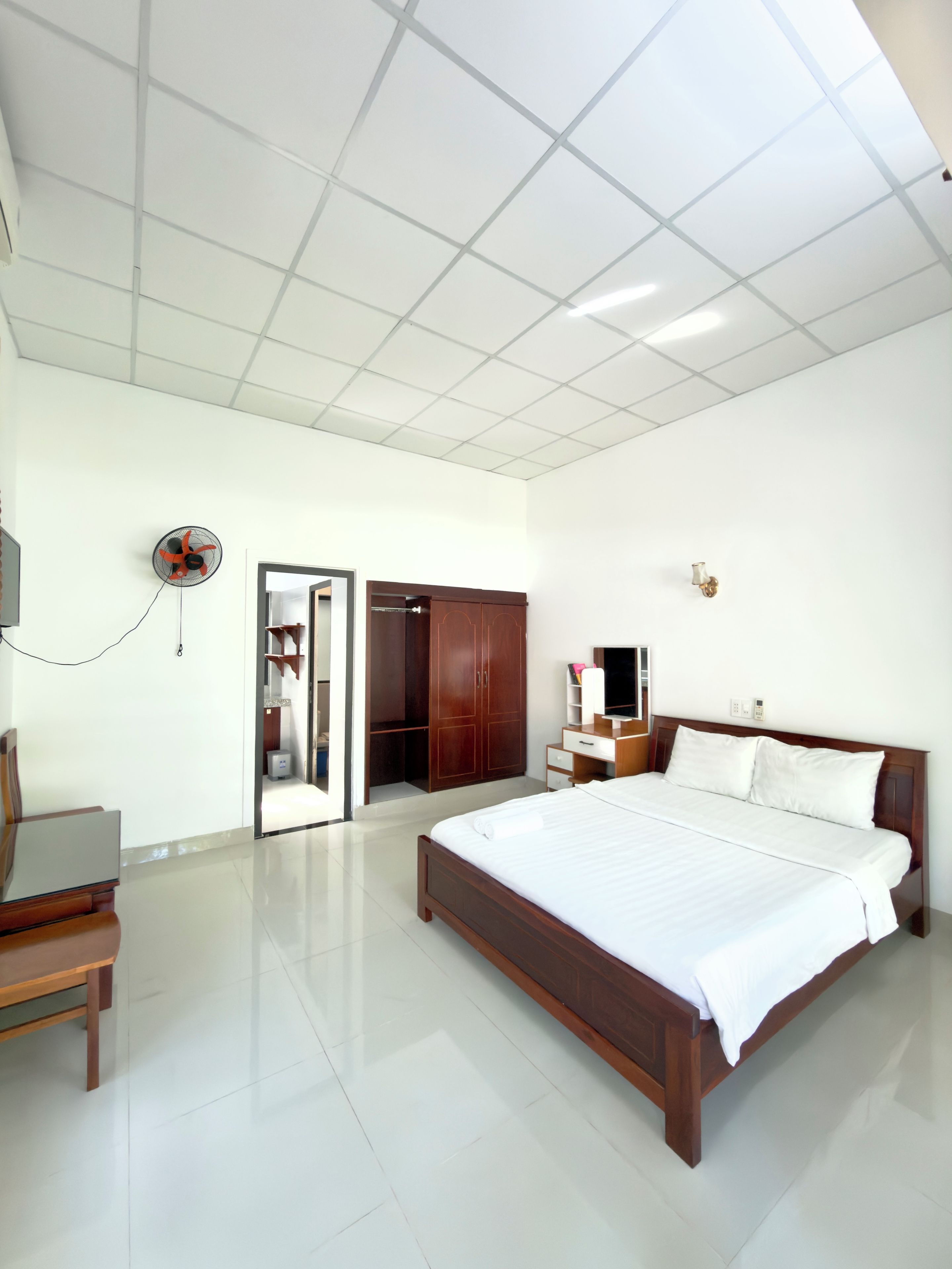 A hotel room with a large bed, a desk, a wardrobe, and a television.
