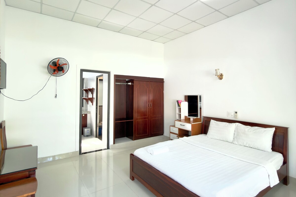 Una habitación de hotel con una cama grande, un escritorio, un armario y un televisor.