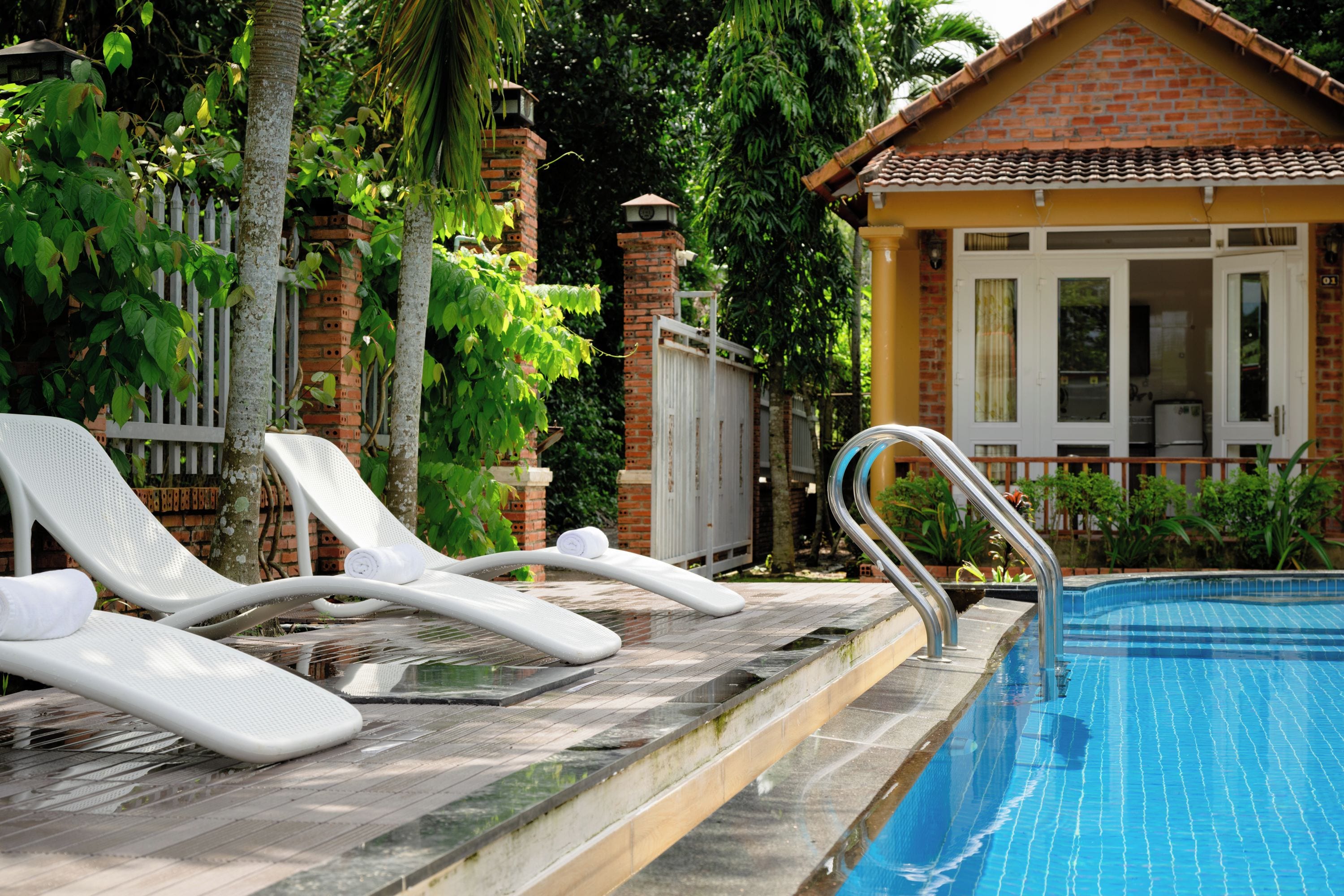 A swimming pool with white lounge chairs and a metal ladder.