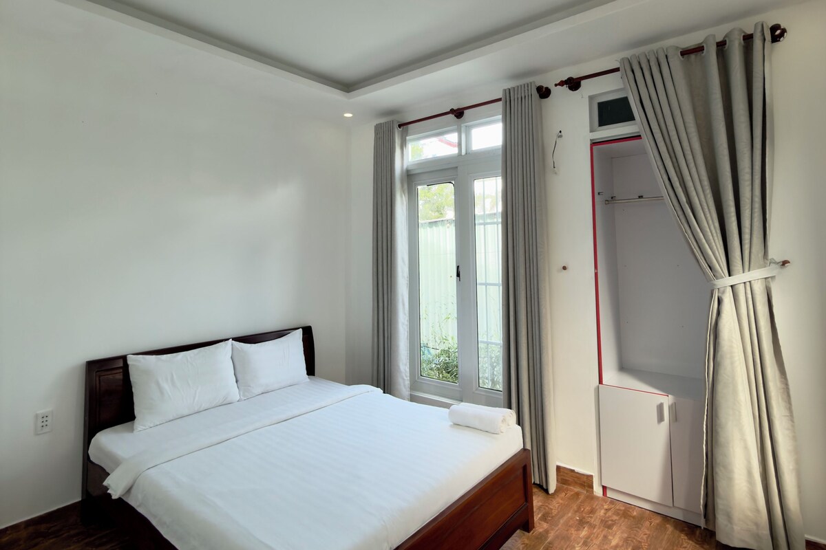 Un dormitorio con una cama grande, un armario y una ventana con cortinas.