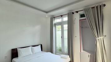 Un dormitorio con una cama grande, un armario y una ventana con cortinas.