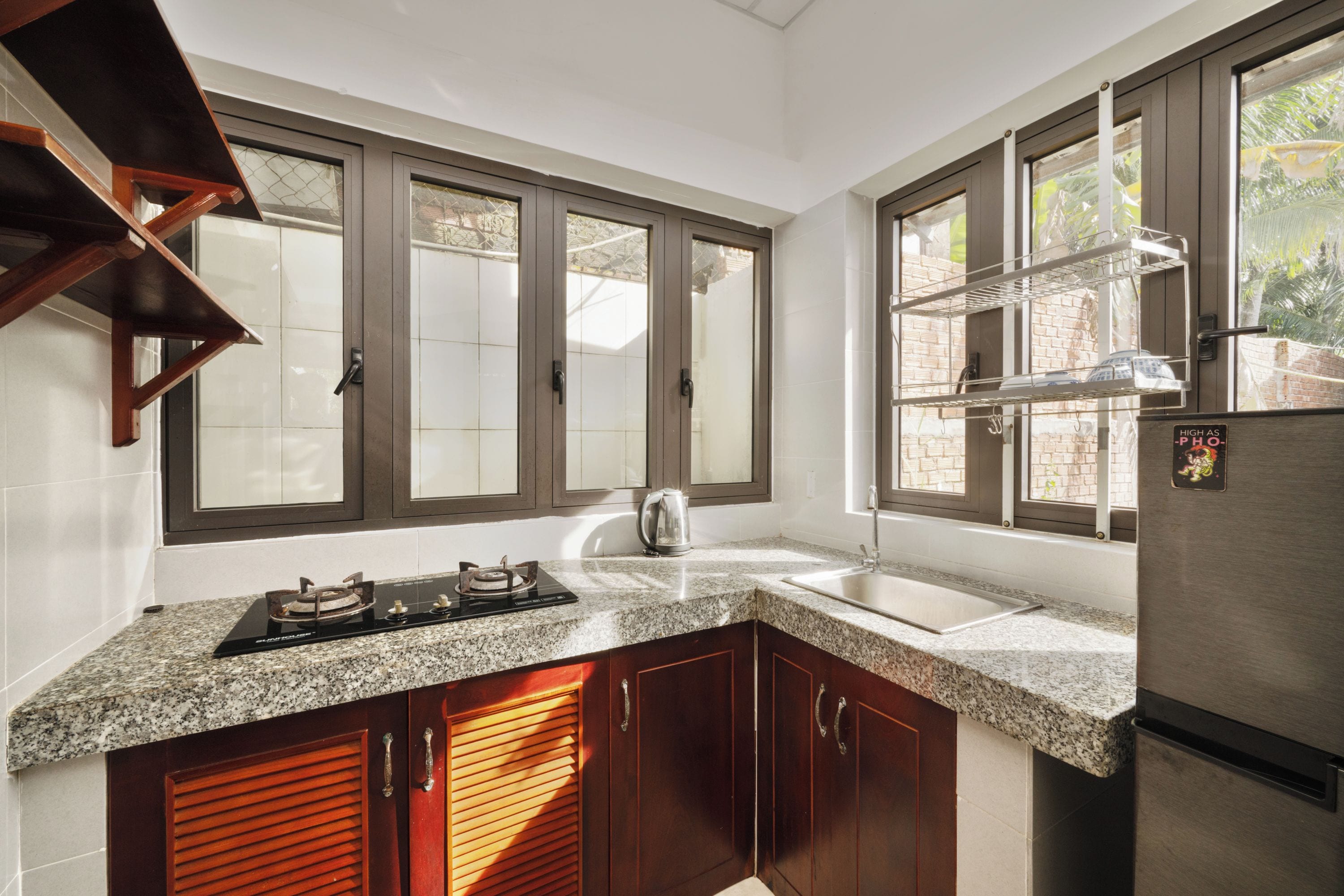 A kitchen with a gas stove, a sink, wooden cabinets, and a stainless steel refrigerator.