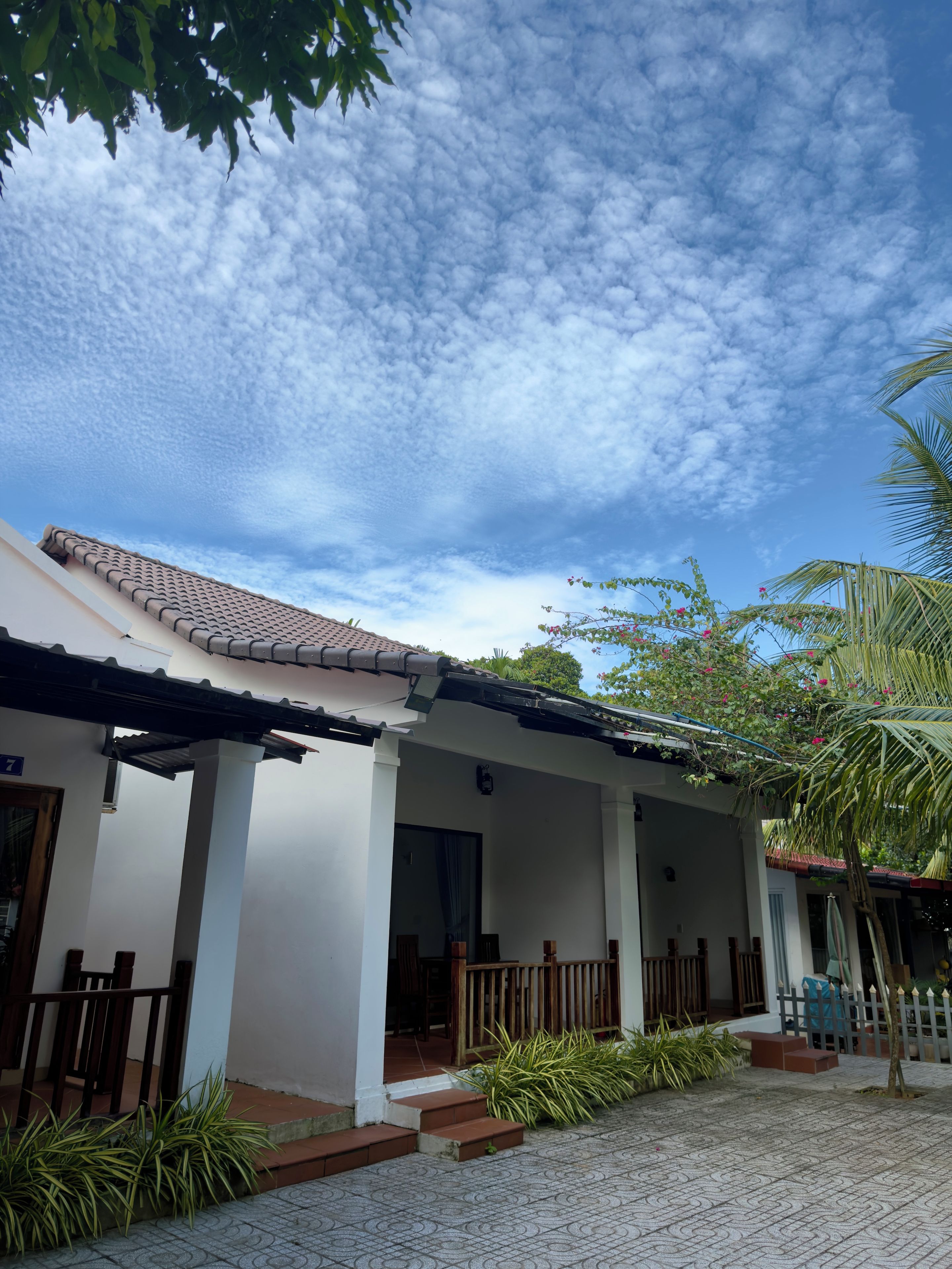 A house with a tiled roof, a covered porch, and a paved entrance area.