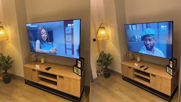 Two televisions mounted on wooden stands with remote controls, a small plant, and a lamp on each stand.