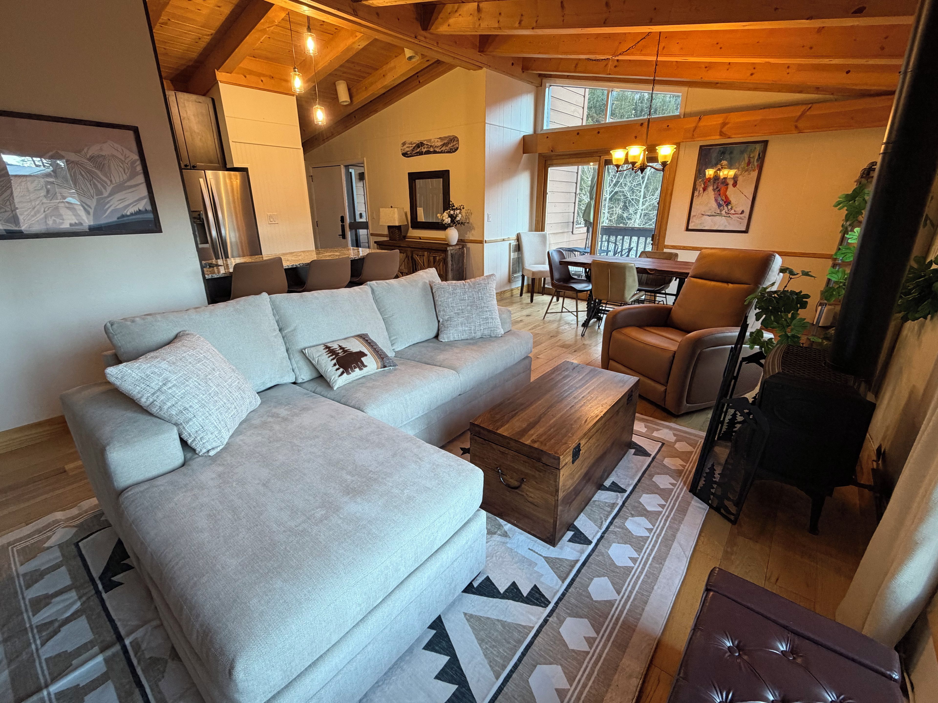 A living room with a sectional sofa, a wooden coffee table, and a patterned rug.