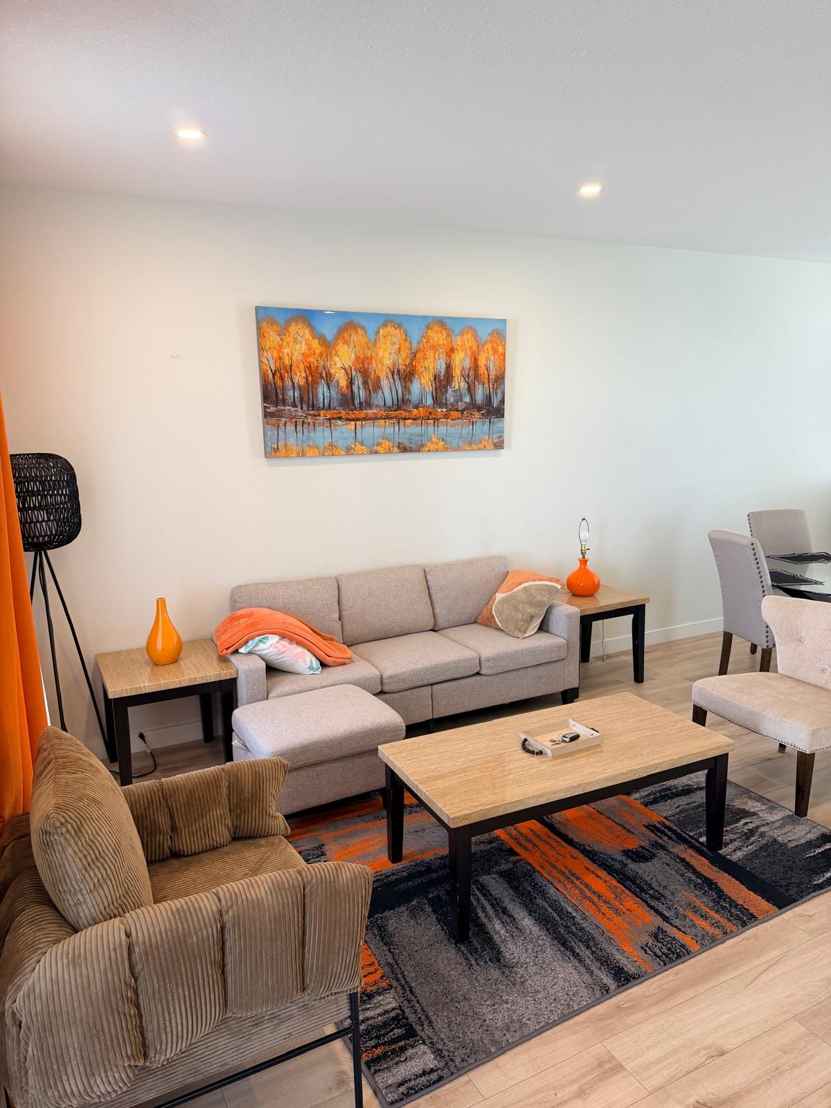 Een moderne woonkamer met een bank, fauteuils, een salontafel en een schilderij aan de muur.