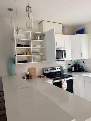 Een moderne keuken met witte kasten, een roestvrijstalen fornuis en een magnetron.