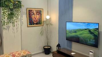 Ein modernes Wohnzimmer mit einem Flachbildfernseher, einem Holztisch, einer Couch und einer Topfpflanze.