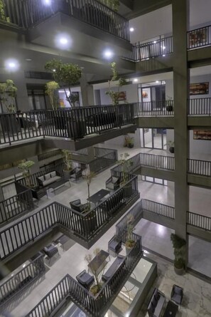 A multi-level interior with balconies, seating areas, and potted plants. - Serenity SkyParkOne Luxury 2BR Apartment (Islamabad)
