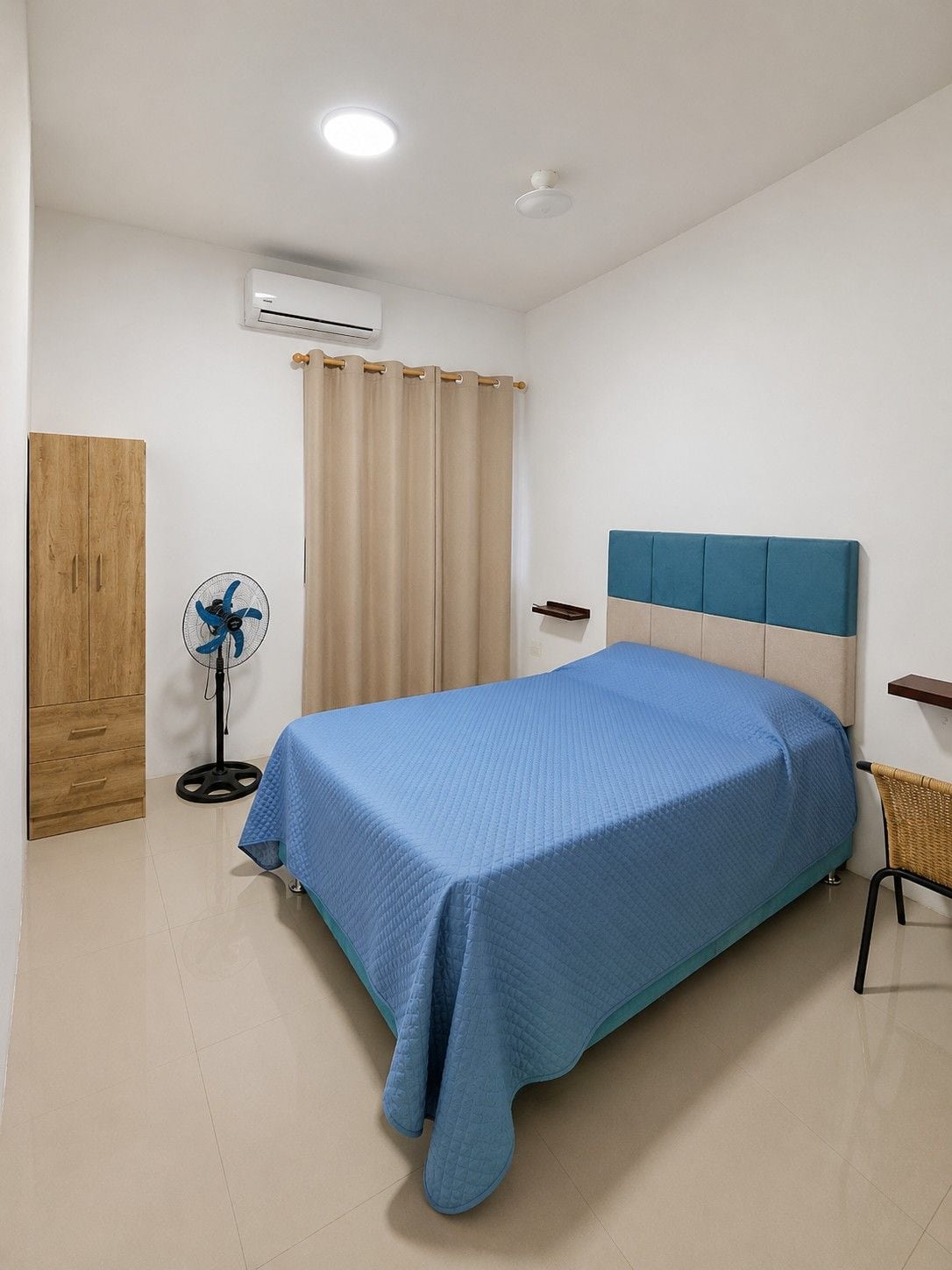 Une chambre à coucher comprenant un lit, un ventilateur, une armoire et un appareil de climatisation.