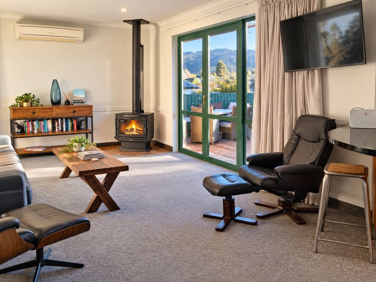 Ein Wohnzimmer mit Kamin, einer Couch, einem Sessel, einem Couchtisch und einem Bücherregal.