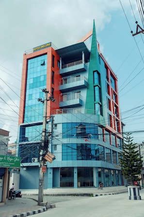 A multi-story hotel with a modern facade, featuring a prominent spire and a mix of glass and solid panels. - Hotel Melung (Kathmandu)