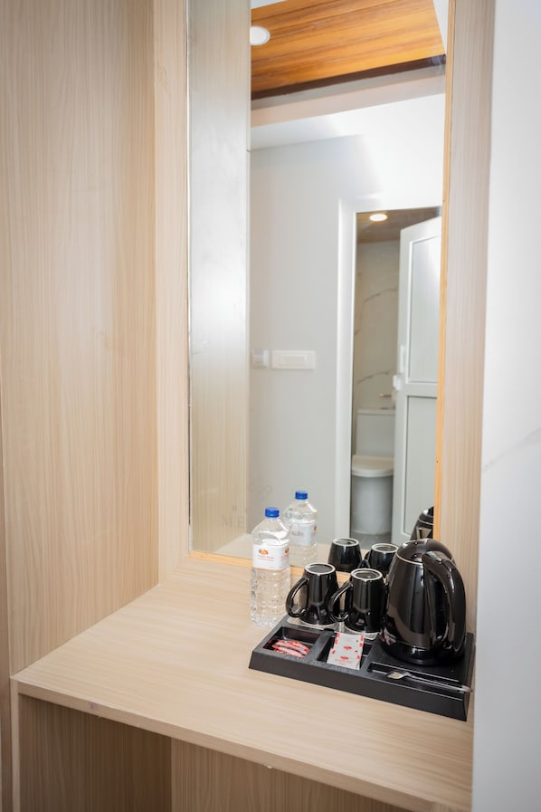 A hotel room with a wooden vanity, a mirror, and a coffee station with cups and a kettle. - Hotel Melung (Kathmandu)