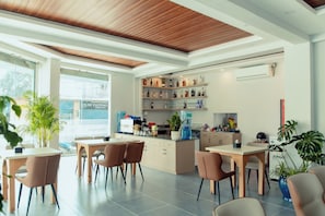 A modern hotel lobby with a wooden ceiling, a bar area with shelves of liquor bottles, a water dispenser, and seating arrangements. - Hotel Melung (Kathmandu)