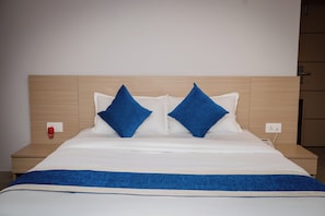 A bed with a wooden headboard, white bedding, and two blue pillows. - Hotel Melung (Kathmandu)