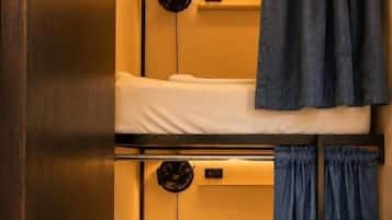 A bunk bed room with a ladder, a small table, and a wall-mounted clock.