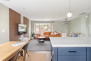 Een moderne woonkamer met een bank, een televisie, een eettafel en een keuken met een groot kookeiland.