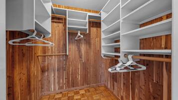 Ein begehbarer Kleiderschrank mit Holzboden, weißen Regalen und Holzvertäfelung.