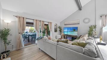Ein modernes Wohnzimmer mit Sofa, Fernseher und Essbereich.