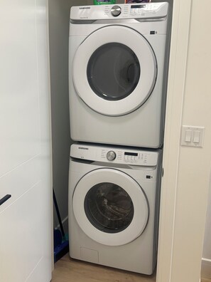 A stacked washer and dryer unit in a laundry room. - Luxury Elegant Condo Prime Location & Parking (Calgary)