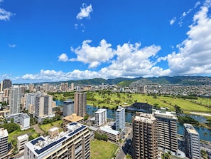 Paisagem urbana com edifícios altos, um rio e montanhas ao fundo.