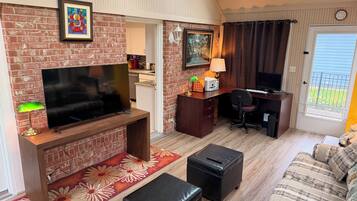 A compact living space with a TV, desk, computer, and seating area.