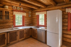 A kitchen with wooden walls, a white refrigerator, a sink, and cabinets.