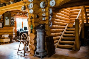A rustic interior with a wooden spiral staircase, a vintage stove, and a collection of plates on the wall.