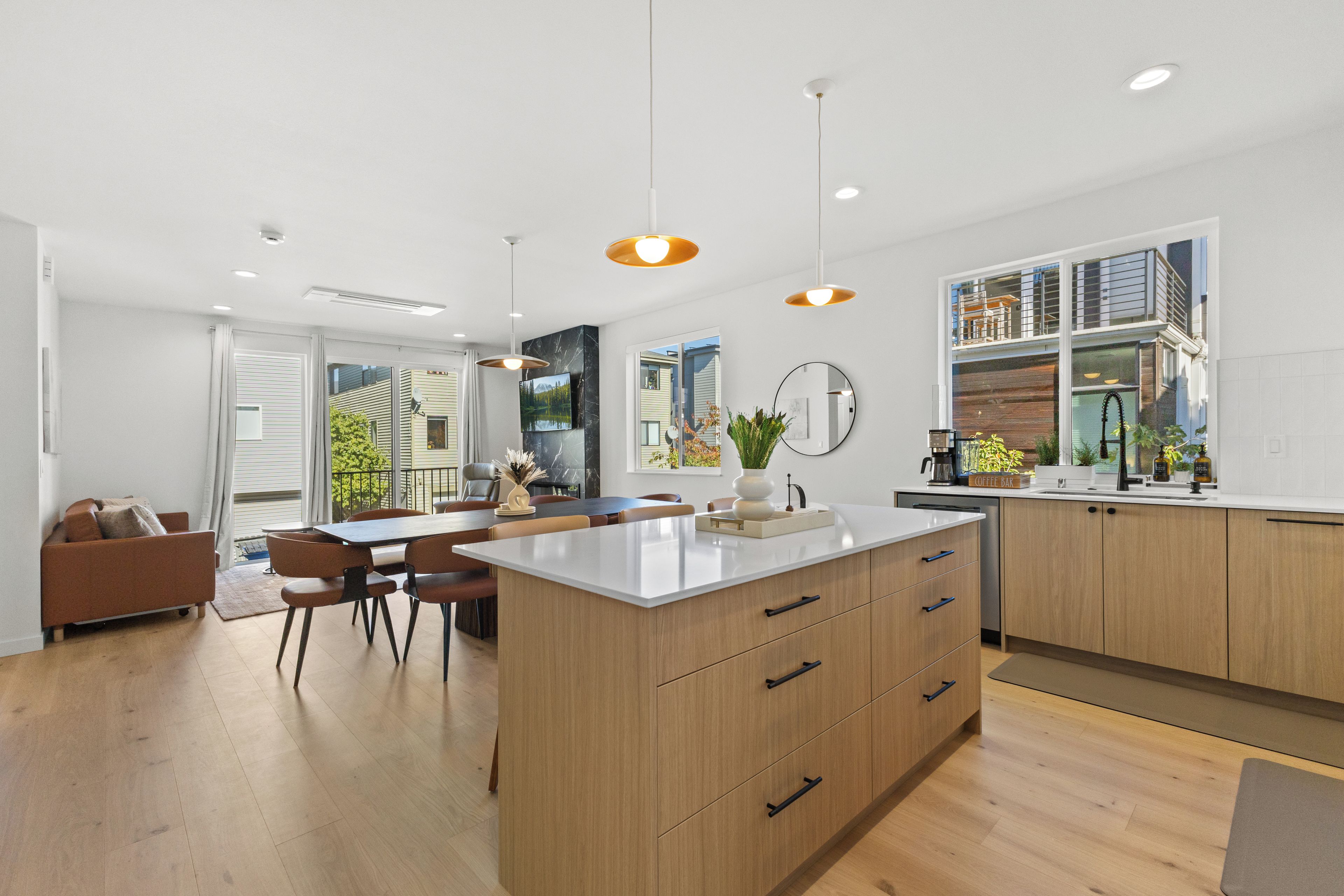 A modern kitchen with wooden cabinets, a central island, and pendant lighting.
