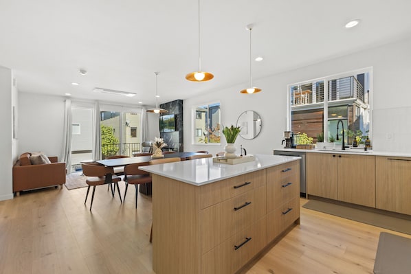 A modern kitchen with wooden cabinets, a central island, and pendant lighting.