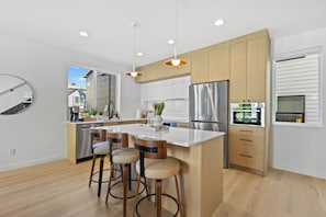 A modern kitchen with a central island, stainless steel appliances, and wooden cabinetry.