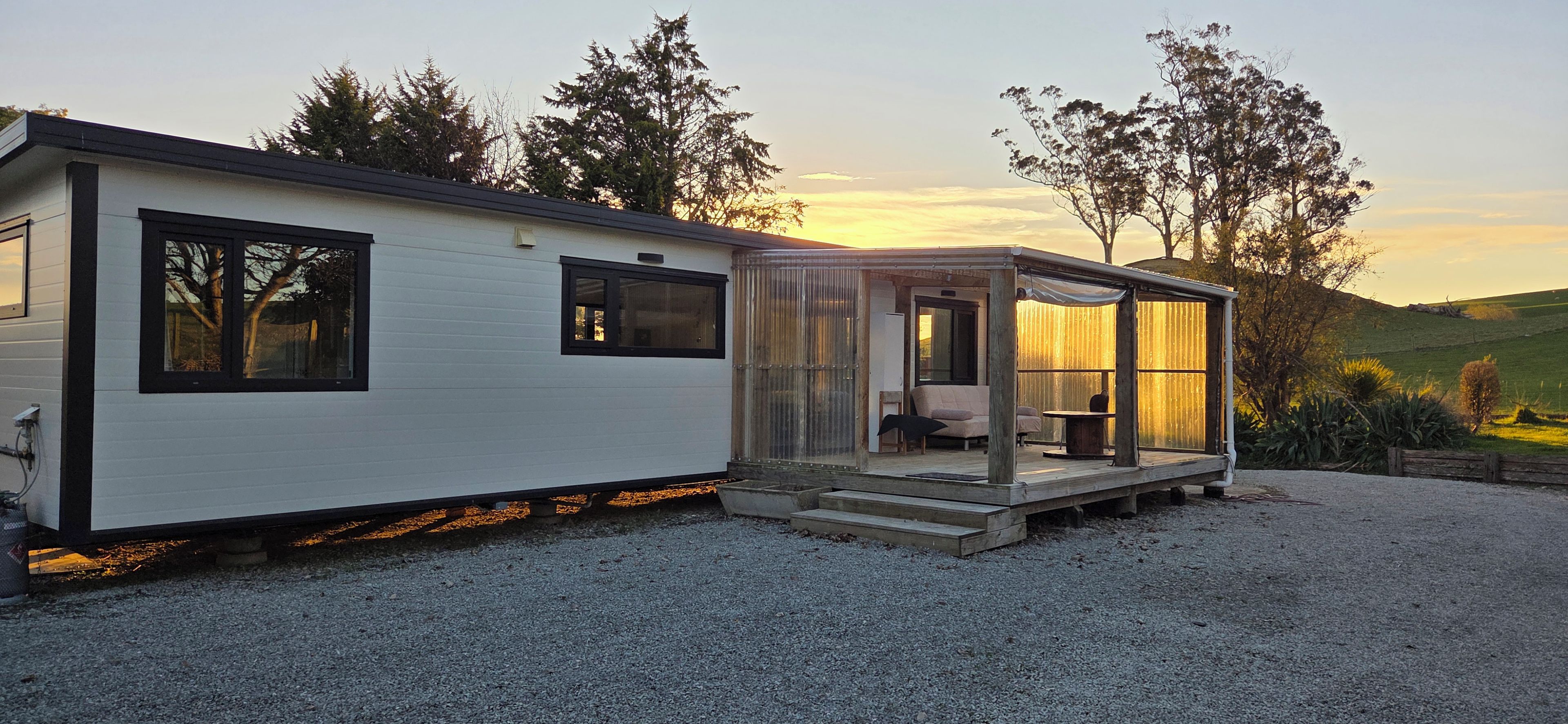 A mobile home with a porch area, a small deck, and a gravel driveway.