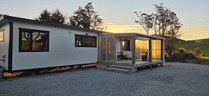 Ein Wohnmobil mit einer Veranda, einer kleinen Terrasse und einem Schotterweg.
