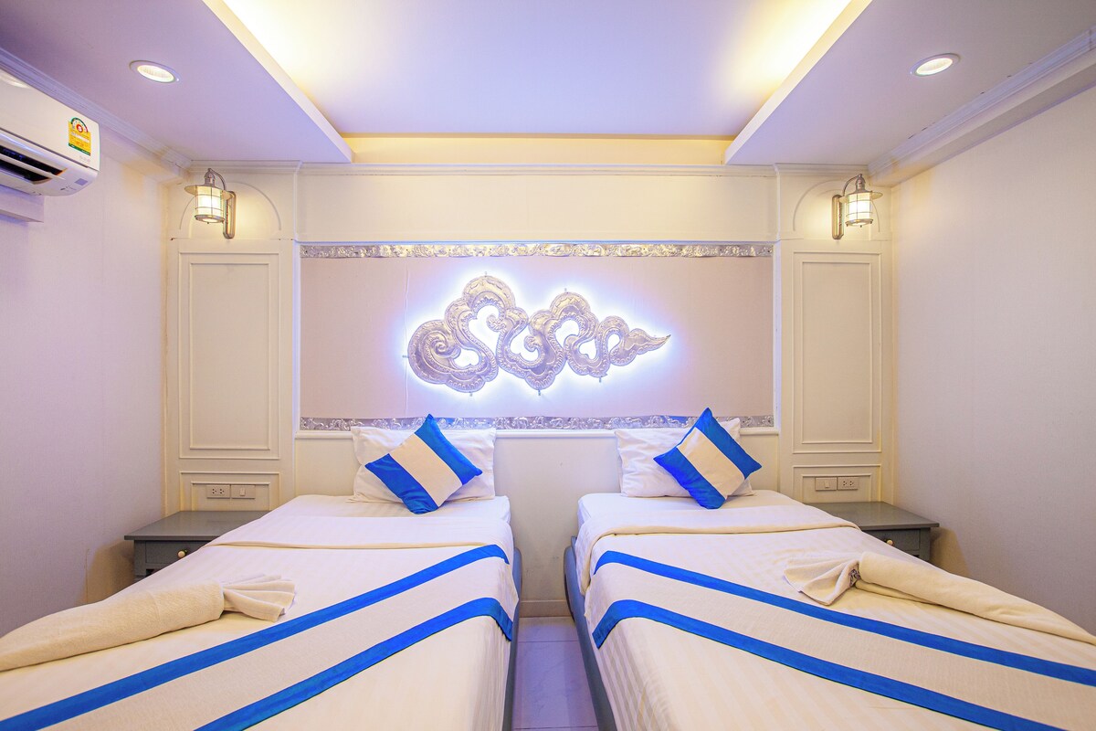 A hotel room with two beds, a decorative wall piece, and a ceiling light fixture.