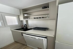 A compact kitchen with a dishwasher, a sink, and a refrigerator. - Apartment on the beachfront in La Fossa with ocean and pool views. (Calpe)