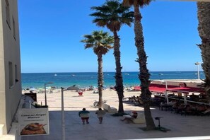 A beach view with palm trees, a clear sky, and a sign for 'Casa del Angel Blanco'. - Apartment on the beachfront in La Fossa with ocean and pool views. (Calpe)