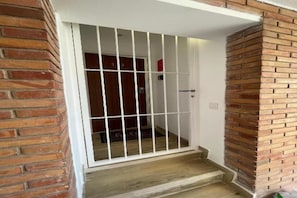 Paret exterior de maó amb una porta blanca i una reixa metàl·lica.
