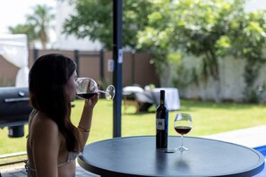 A person seated at a round table outdoors with a bottle of wine and a glass on it. - 2 adjoining country homes with 2 heated pools, 2 terraces, and a garden (Jardines de la calera)