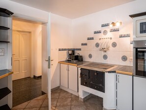 A compact kitchen with a built-in stove, a coffee machine, and a microwave. - Holiday home with panoramic views (Hopfgarten im Brixental)