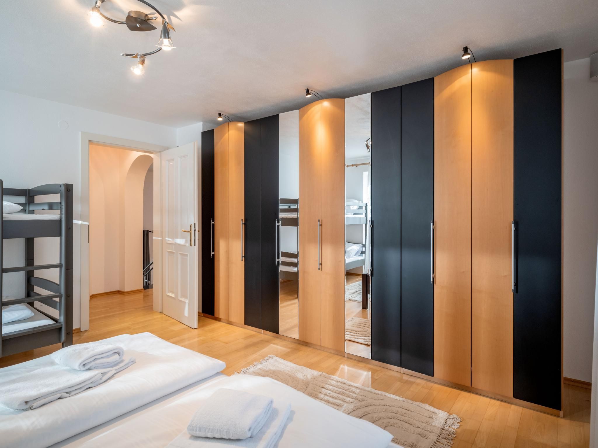 Une chambre avec un lit superposé, une armoire aux portes noires et en bois, et une table de chevet avec des serviettes.