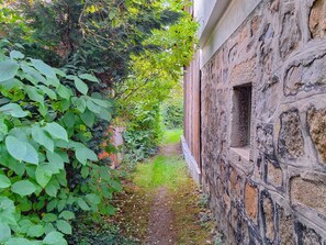 Ein schmaler Steinweg, gesäumt von üppiger Vegetation und einer Steinmauer.
