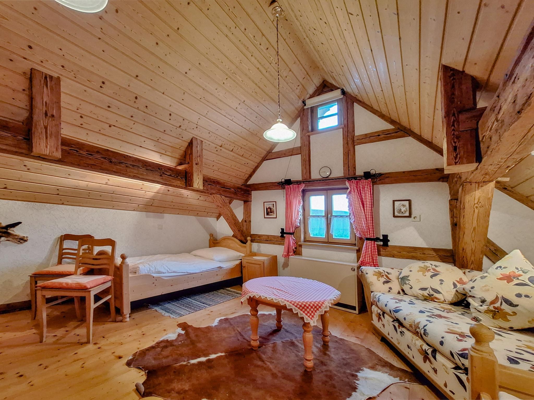 Una habitación acogedora con una cama, un sofá, una mesa y una alfombra de piel de vaca.