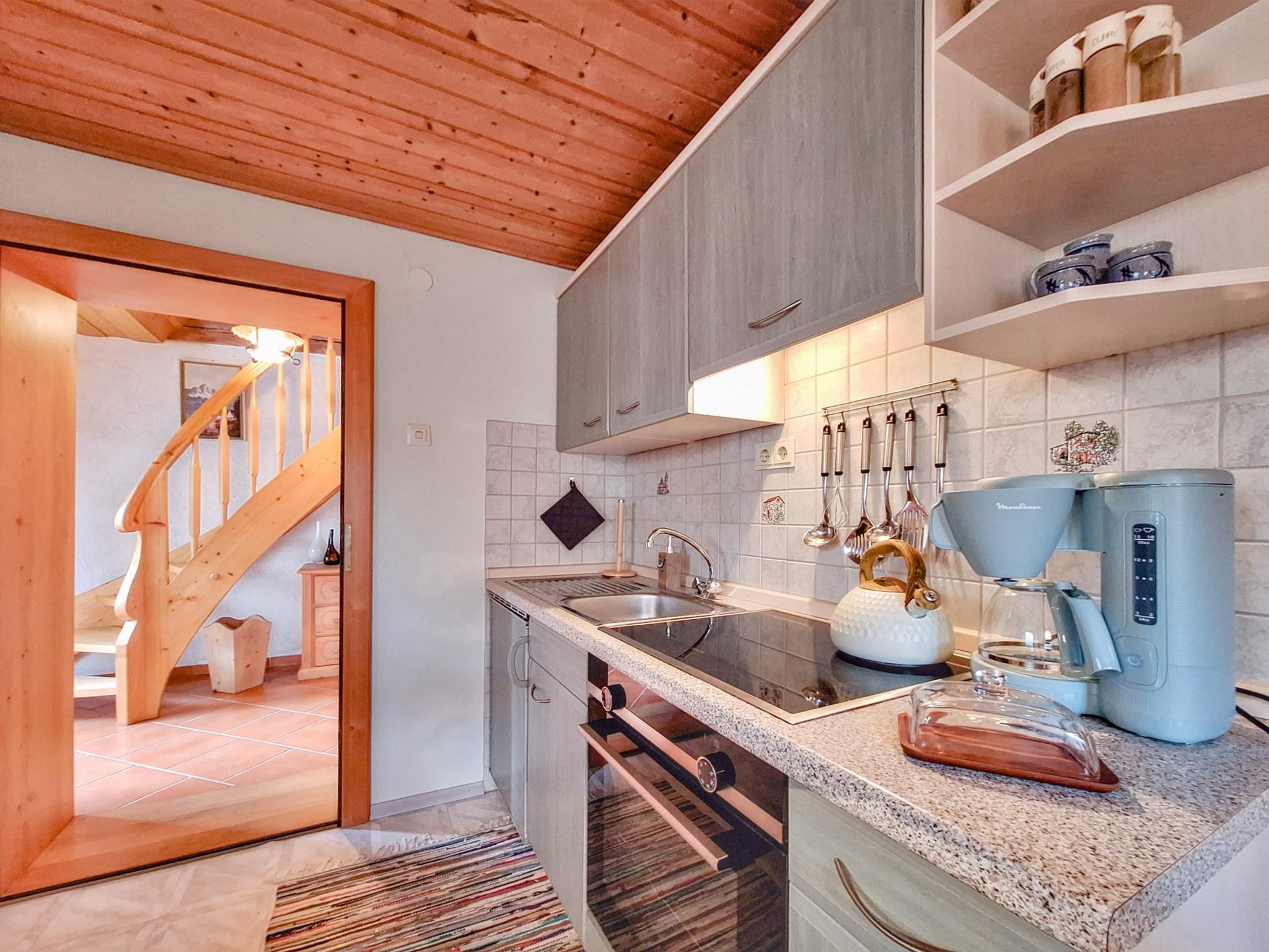 Una cocina moderna con escalera de madera, encimeras de granito y electrodomésticos de acero inoxidable.