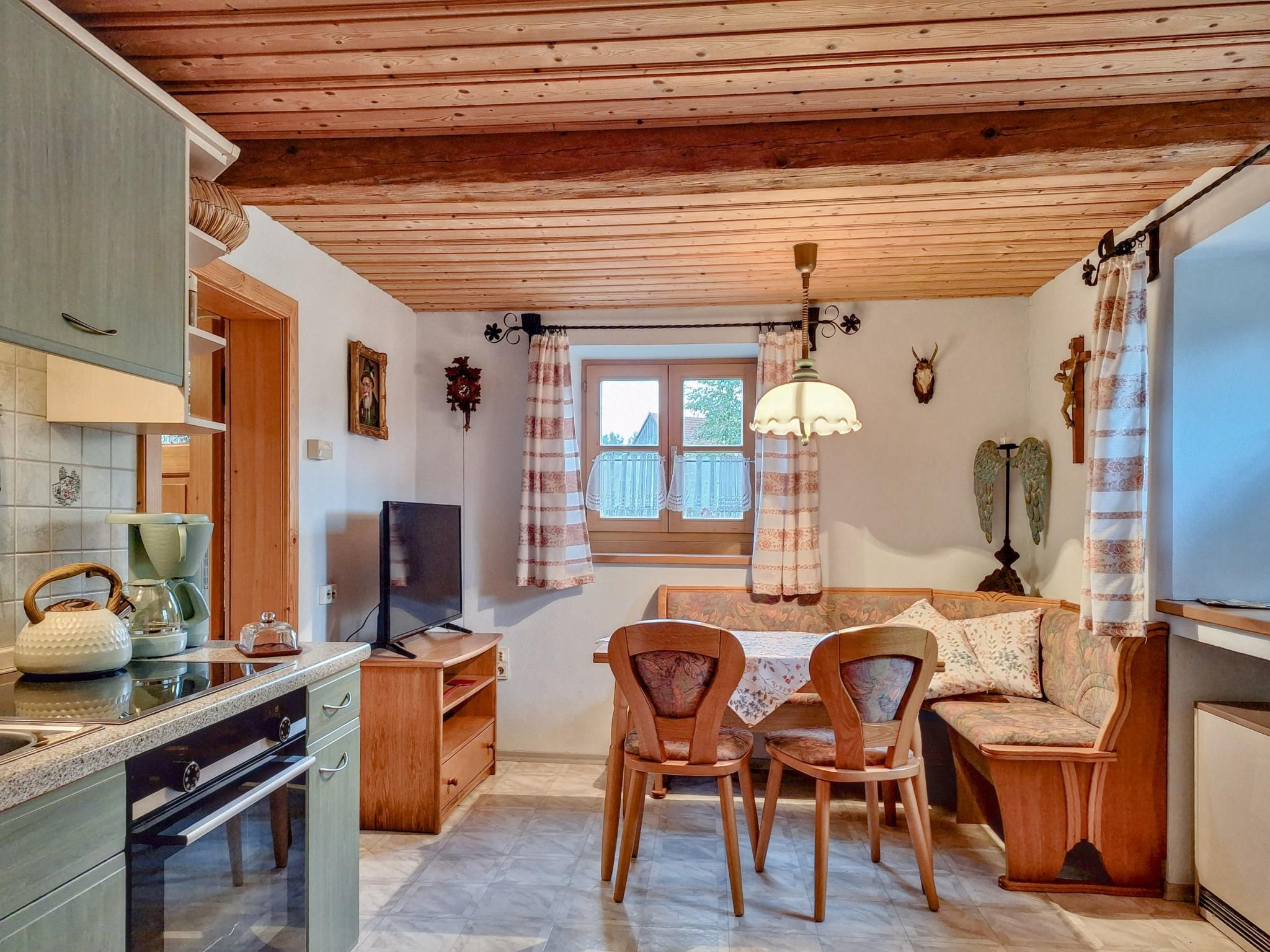 Una cocina compacta con comedor, techo de madera y televisor.